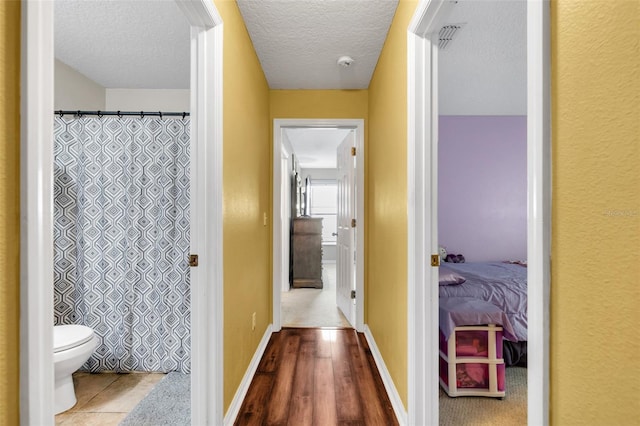 corridor with a textured ceiling and hardwood / wood-style flooring