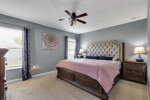 bedroom with light colored carpet, ceiling fan, a textured ceiling, and multiple windows