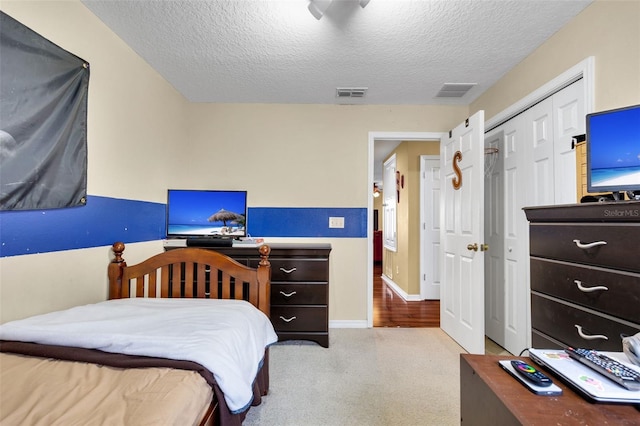 carpeted bedroom featuring a closet and a textured ceiling