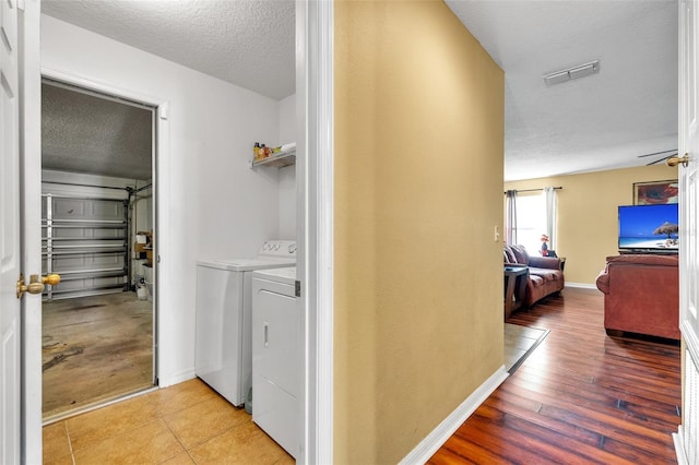 hallway featuring washer and dryer, a textured ceiling, and light tile floors