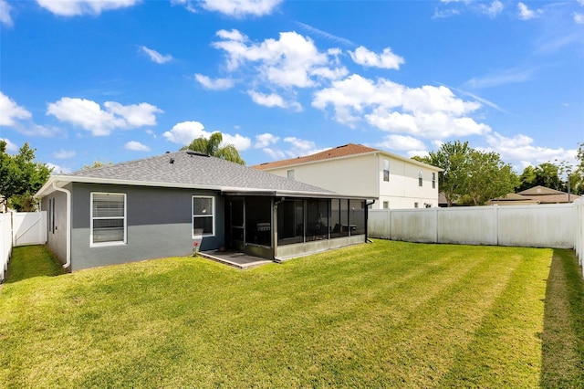 rear view of house featuring a sunroom and a lawn