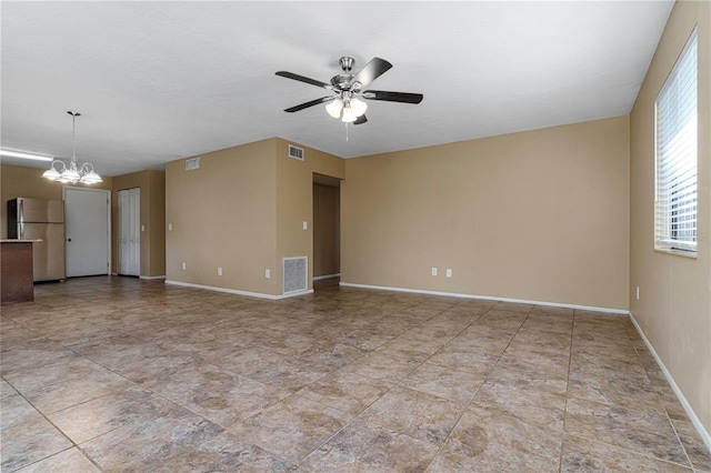 tiled empty room with ceiling fan with notable chandelier