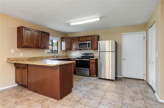 kitchen with sink, appliances with stainless steel finishes, light tile floors, and kitchen peninsula