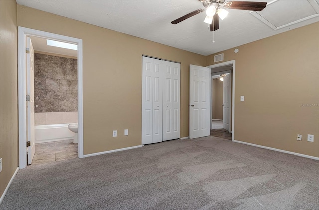 unfurnished bedroom featuring ceiling fan, light colored carpet, and ensuite bath