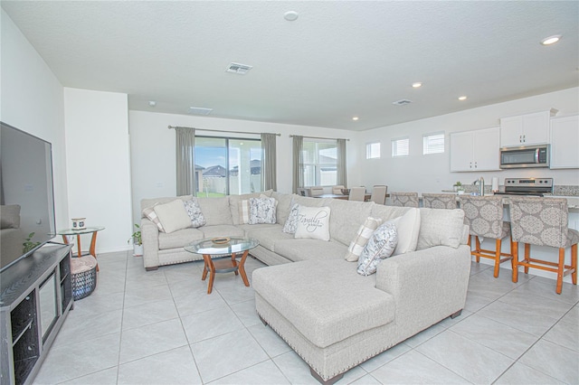 living room featuring sink, light tile patterned floors, and a textured ceiling