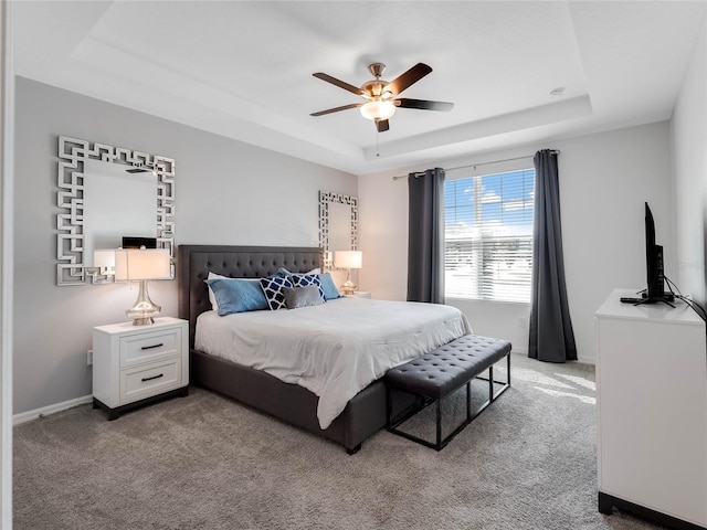 carpeted bedroom with a tray ceiling and ceiling fan