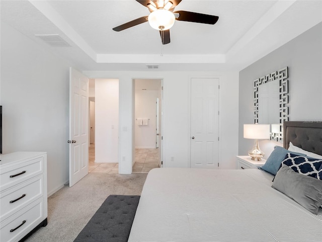 bedroom featuring a tray ceiling, ceiling fan, and light colored carpet