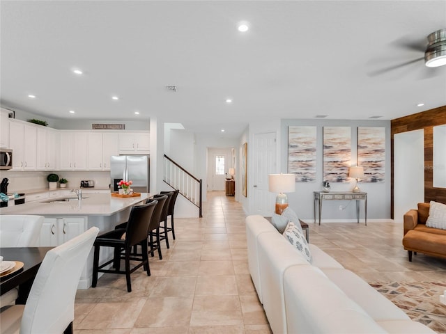 tiled living room with ceiling fan and sink