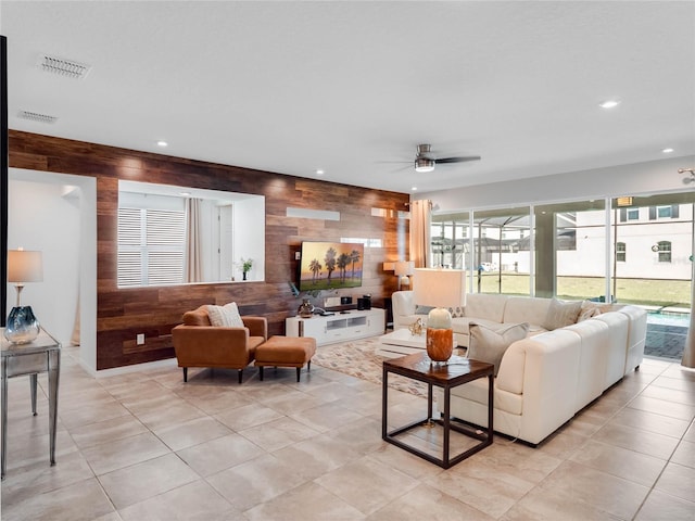 tiled living room featuring wooden walls and ceiling fan