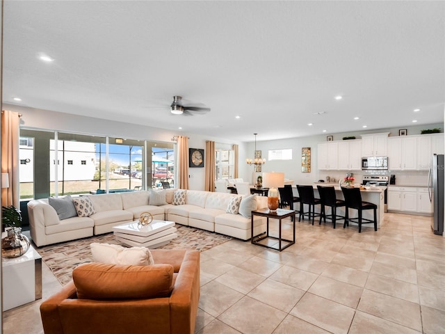 tiled living room featuring ceiling fan with notable chandelier