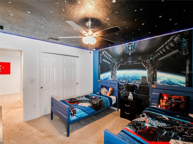 carpeted bedroom with ceiling fan and a textured ceiling