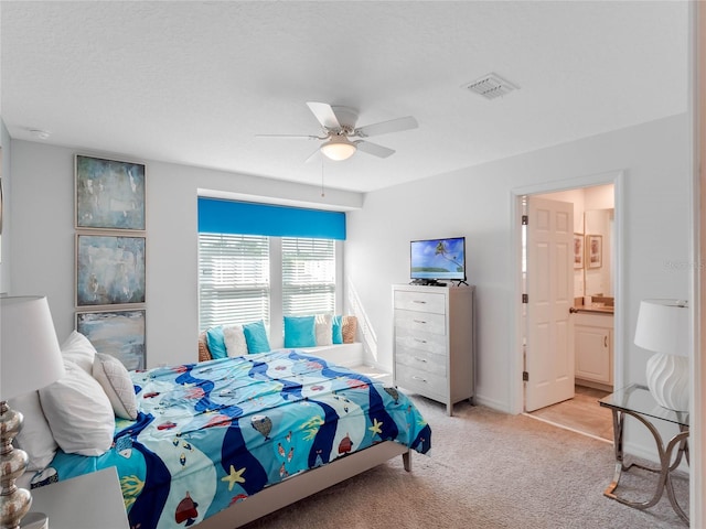 bedroom featuring connected bathroom, light colored carpet, and ceiling fan