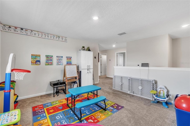 playroom featuring a textured ceiling and light colored carpet