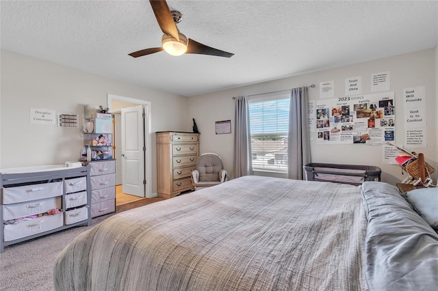 bedroom with ceiling fan, a textured ceiling, and light colored carpet