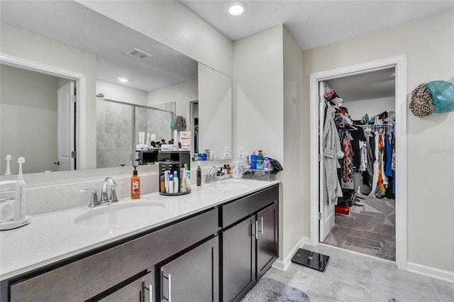 bathroom with an enclosed shower, double sink, tile floors, and vanity with extensive cabinet space