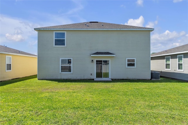 rear view of property with central air condition unit and a lawn