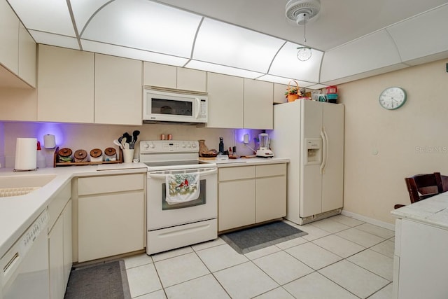 kitchen featuring light tile floors, cream cabinetry, and white appliances