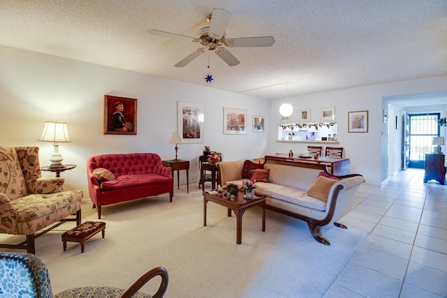 living room with light tile floors, ceiling fan, and a textured ceiling