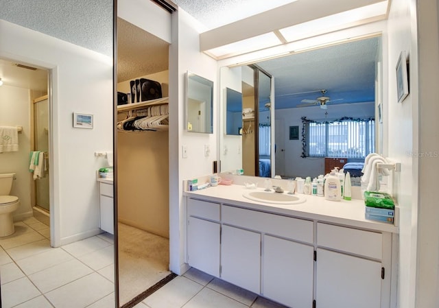 bathroom with toilet, large vanity, ceiling fan, a textured ceiling, and tile flooring