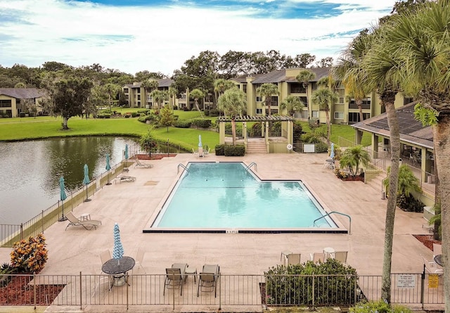 view of pool with a lawn, a water view, and a patio area