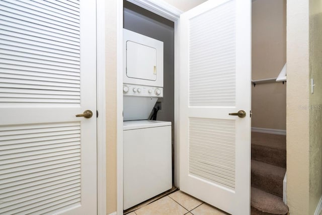 clothes washing area featuring stacked washer and clothes dryer and light tile patterned flooring