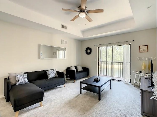 carpeted living room featuring a tray ceiling and ceiling fan