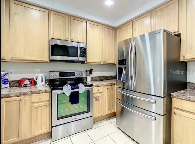 kitchen with light brown cabinets, light stone counters, light tile flooring, and stainless steel appliances