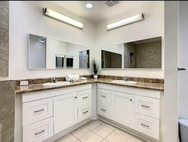 bathroom with toilet, dual bowl vanity, and tile floors