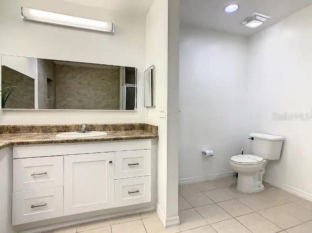 bathroom with toilet, vanity, and tile flooring