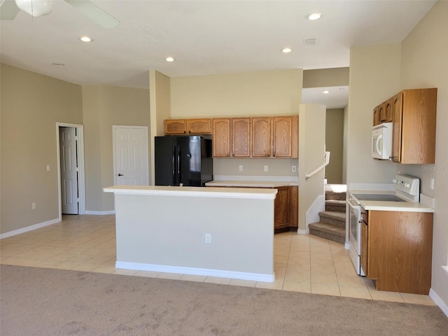 kitchen featuring light colored carpet, ceiling fan, a center island, and white appliances