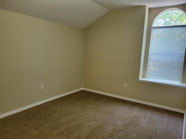 carpeted empty room featuring vaulted ceiling