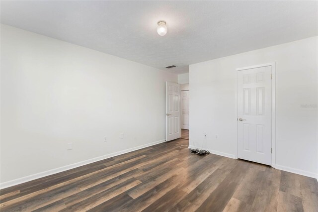 unfurnished bedroom with a textured ceiling and dark wood-type flooring