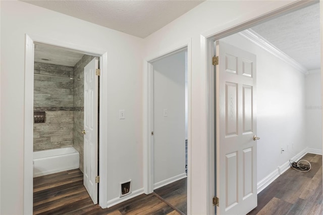 corridor featuring a textured ceiling, ornamental molding, and dark hardwood / wood-style flooring