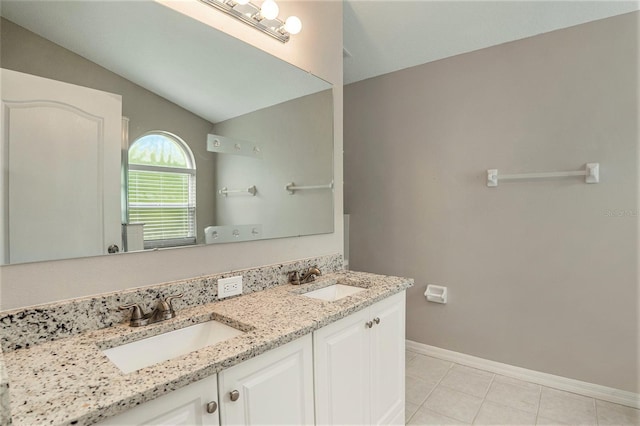 bathroom with dual vanity, tile floors, and vaulted ceiling