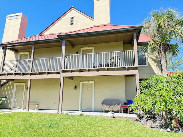 back of property with a balcony and a yard