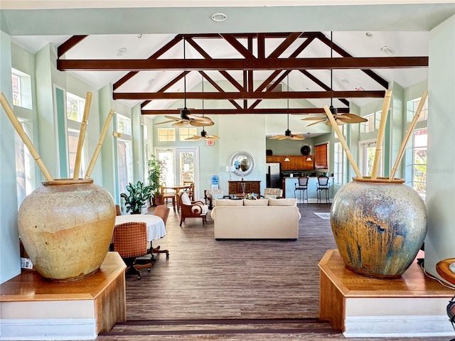 living room with a wealth of natural light, beam ceiling, hardwood / wood-style flooring, and ceiling fan