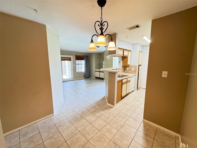 kitchen with light tile patterned flooring, black electric cooktop, a textured ceiling, backsplash, and decorative light fixtures