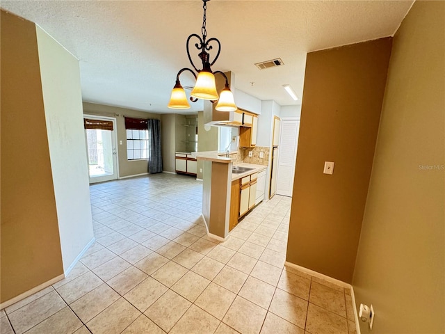 kitchen with a notable chandelier, light tile patterned flooring, hanging light fixtures, a textured ceiling, and backsplash