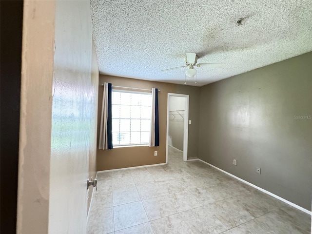 tiled empty room with a textured ceiling and ceiling fan