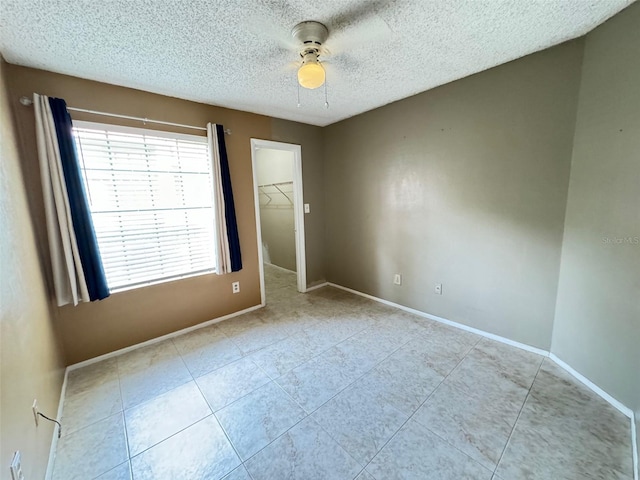 tiled spare room with a textured ceiling and ceiling fan