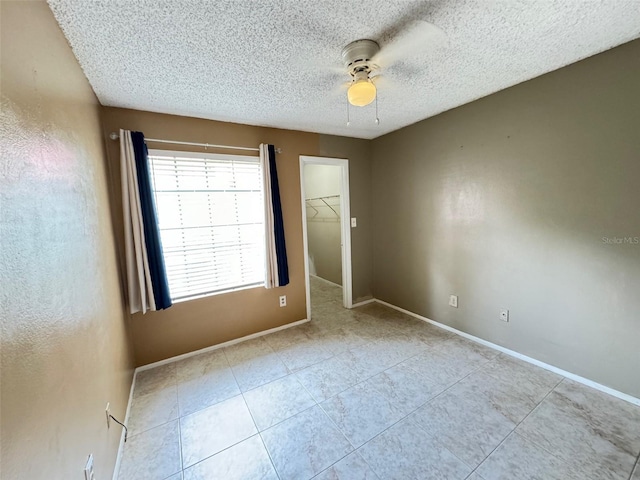 unfurnished bedroom with a closet, a spacious closet, ceiling fan, a textured ceiling, and light tile patterned floors