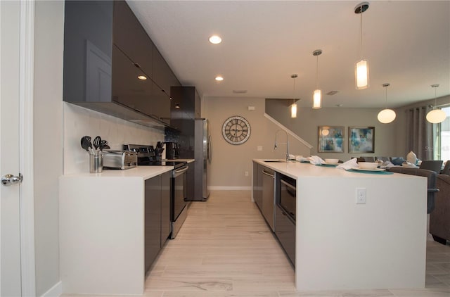 kitchen with hanging light fixtures, sink, light hardwood / wood-style flooring, stainless steel appliances, and tasteful backsplash