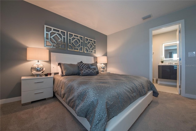 carpeted bedroom featuring ensuite bathroom and sink