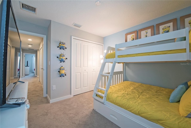 bedroom with a closet, light carpet, and a textured ceiling