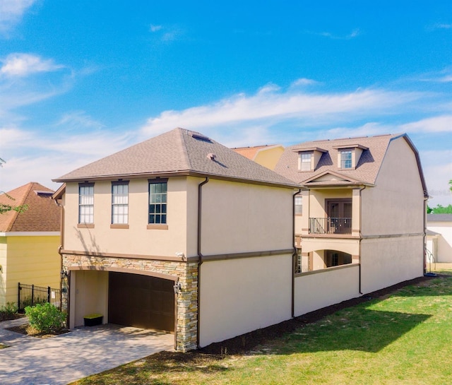 view of side of home featuring stucco siding, fence, a garage, stone siding, and driveway