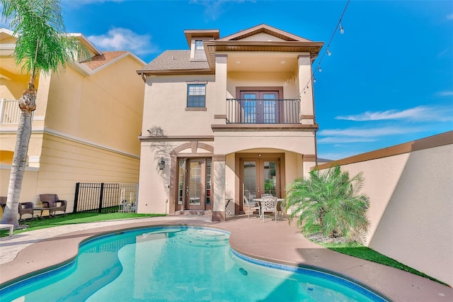 back of house with french doors, a balcony, and a patio