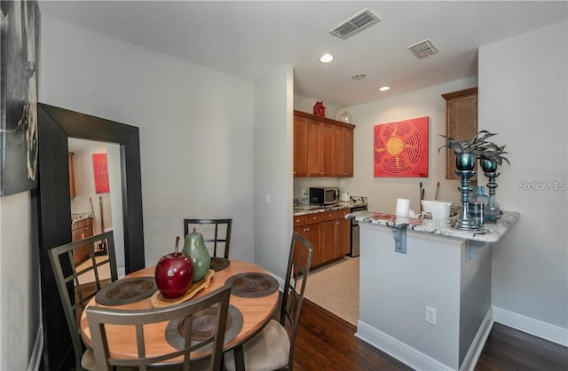 kitchen featuring light stone counters, kitchen peninsula, and dark hardwood / wood-style flooring