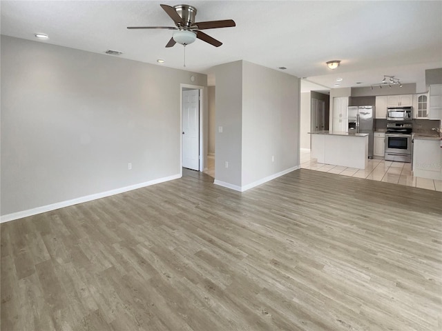 unfurnished living room featuring light hardwood / wood-style flooring and ceiling fan