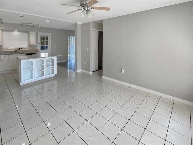 interior space with ceiling fan, light tile patterned flooring, a kitchen island, and white cabinetry