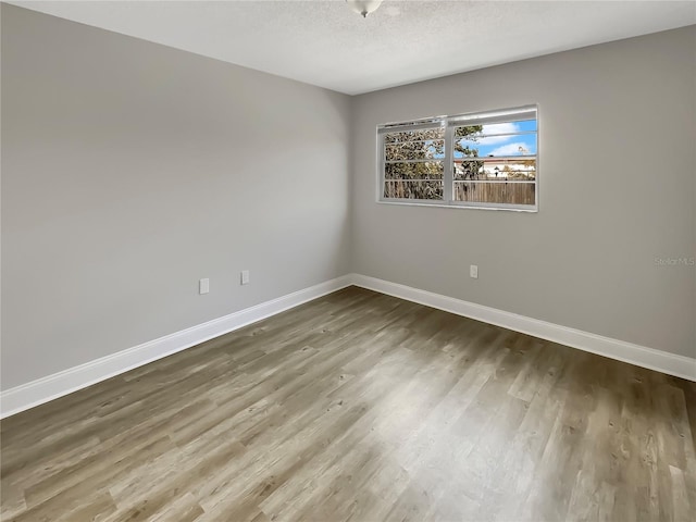 spare room featuring wood-type flooring and a textured ceiling